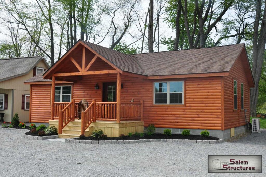 Premium modular log cabin by Salem Structures featuring a covered porch, rustic wood exterior, and residential-style windows—ideal for vacation homes or hunting cabins.
